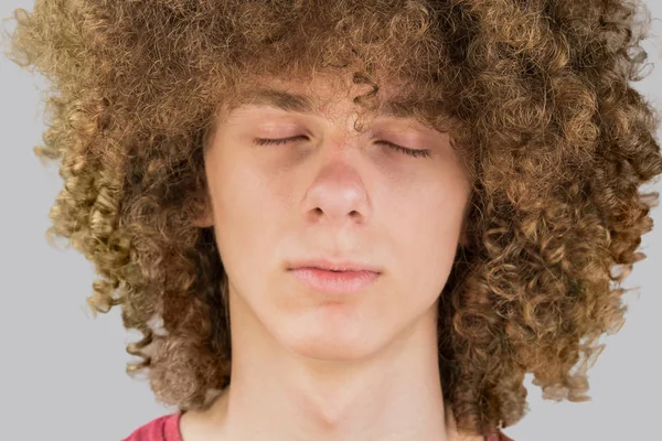 Cropped portrait of a young curly European man with long curly hair and closed eyes close up. very lush male hair. curling hair for men. a lock of passion. isolated on gray background — Stock Photo, Image
