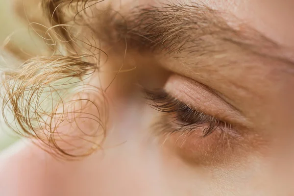 male eye close up. a curl of curly hair hangs over a man\'s face. thoughtful look into the void