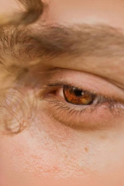 Ojo masculino de cerca. un rizo de pelo rizado cuelga sobre la cara de un hombre. mirada reflexiva en el vacío —  Fotos de Stock