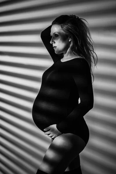 A pregnant woman in lingerie with a big belly in the ninth month of pregnancy is posing next to a big five-pointed star. in anticipation of childbirth — Stock Photo, Image