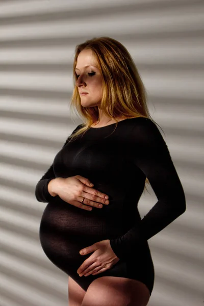 Těhotná žena ve spodním prádle s velkým břichem v devátém měsíci těhotenství objímá břicho. v očekávání porodu — Stock fotografie