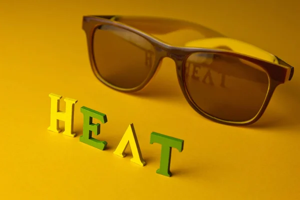 Concept de protection thermique sur la plage. Brille inscription sur fond jaune avec des lunettes de soleil. vue de dessus — Photo