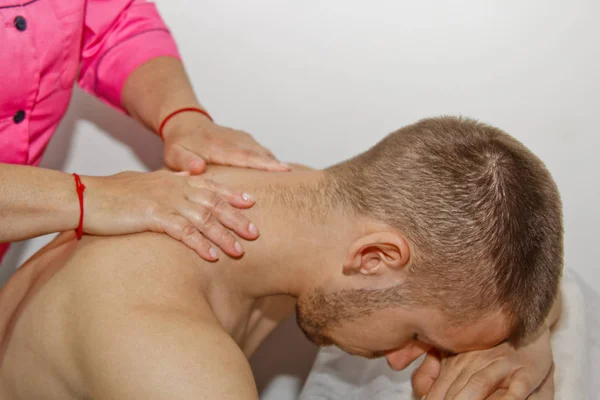 Profesyonel terapötik boyun ve kafa masajı. bir masaj odasında atlet adam. ağrı kurtarma prosedürü. Genç hasta üzerinde manipülatif omurga tedavisi yapan kadın fizyoterapist — Stok fotoğraf