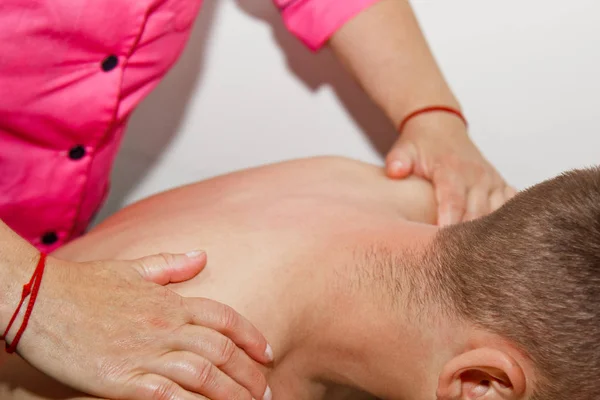 Професійний терапевтичний масаж шиї та голови. людина спортсмен в масажному кабінеті. процедура відновлення болю. Жінка-фізіотерапевт робить маніпулятивне лікування хребта на молодого пацієнта — стокове фото