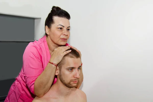 Professionelle therapeutische Nacken- und Kopfmassage. Mann den Athleten in einem Massageraum. Schmerzbehandlung. Physiotherapeutin macht manipulative Wirbelsäulenbehandlung an junger Patientin — Stockfoto