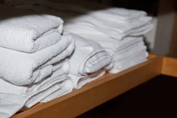 Skręcone białe ręczniki do zabiegów spa są na półce w gabinecie masażu — Zdjęcie stockowe
