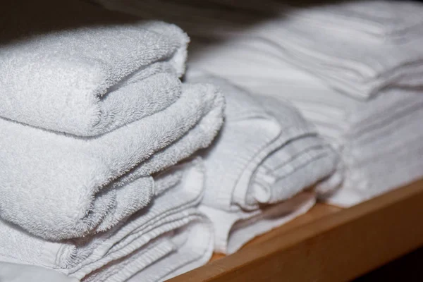 Gedraaide witte handdoeken voor spabehandelingen staan op de plank in de massageruimte — Stockfoto