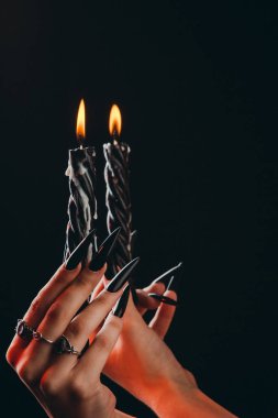 Uzun tırnakları olan kadın elleri siyah izole bir arka plan üzerinde yanan mumlar tutun. cadılar bayramında cadılık cadılık kavramı. parmaklarda gümüş yüzük