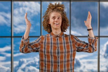 Bir pencerenin arka planda gülümseyen tam saçlı ahşap bir tarak ile kıvırcık saçlı genç bir adamın portresi. erkek saç bakım konsepti