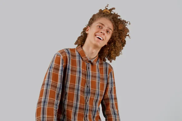 Портрет кудрявого молодого человека с деревянной расческой в полных волосах, улыбающегося на сером изолированном фоне. мужской уход за волосами — стоковое фото