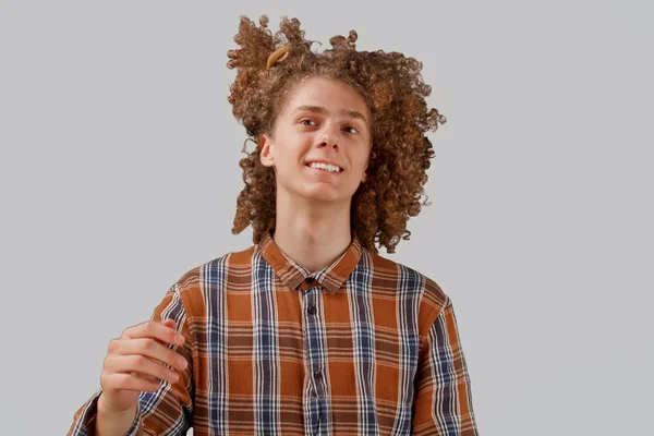 Retrato de um jovem de cabelos encaracolados com um pente de madeira no cabelo cheio sorrindo em um fundo isolado cinza. conceito de cuidado do cabelo masculino — Fotografia de Stock