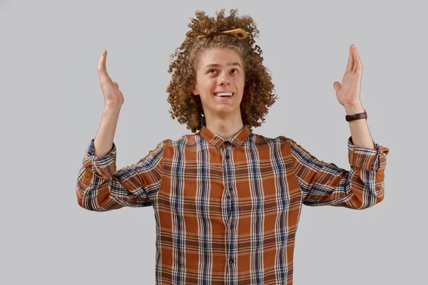 Retrato de um jovem de cabelos encaracolados com um pente de madeira no cabelo cheio sorrindo em um fundo isolado cinza. conceito de cuidado do cabelo masculino — Fotografia de Stock