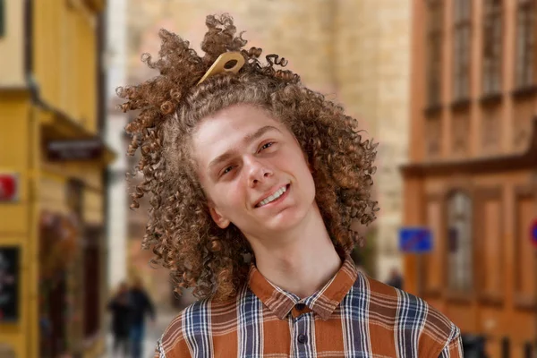 Retrato de un joven de pelo rizado con un peine de madera en pelo completo sonriendo en la calle. concepto de cuidado del cabello masculino — Foto de Stock