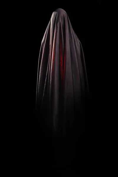 黒い布で覆われた女性は、孤立した黒い背景に立っています。顔のない死の概念 — ストック写真