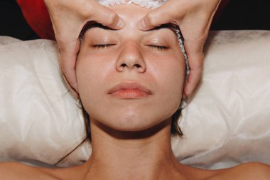 spa uzmanı tıbbi şapkalı genç bir kıza yüz masajı yapıyor. güzellik bakımları yakın çekim