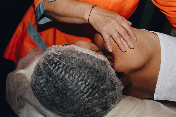 Bir spa uzmanı tıbbi şapkalı genç bir kızın omurgasını büküyor. vücut prosedürleri yakın çekim. sırt ağrısı kurtarma — Stok fotoğraf
