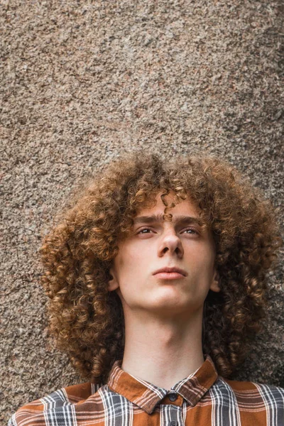 Retrato de um jovem de cabelos encaracolados entre as pedras na rua. conceito de estudante e jovem viajante — Fotografia de Stock