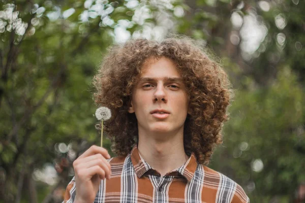 Retrato de um jovem de cabelos encaracolados em um parque de verão na rua. conceito de estudante e jovem viajante — Fotografia de Stock