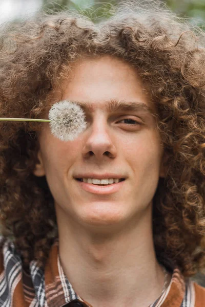 Retrato de um jovem de cabelos encaracolados em um parque de verão na rua. conceito de estudante e jovem viajante — Fotografia de Stock