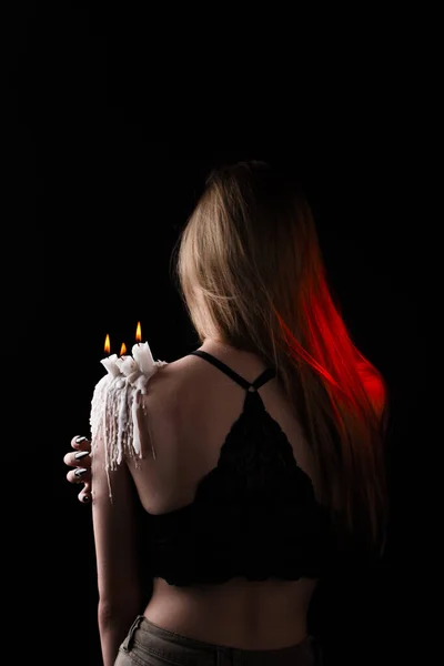 Una chica con el pelo largo en la imagen de una bruja está tratando de prenderse fuego. rituales con velas para hechizo de amor y daño. expulsión de un mal espíritu del cuerpo — Foto de Stock