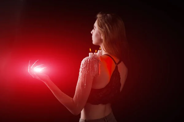 Una chica con el pelo largo en la imagen de una bruja está tratando de prenderse fuego. rituales con velas para hechizo de amor y daño. expulsión de un mal espíritu del cuerpo — Foto de Stock