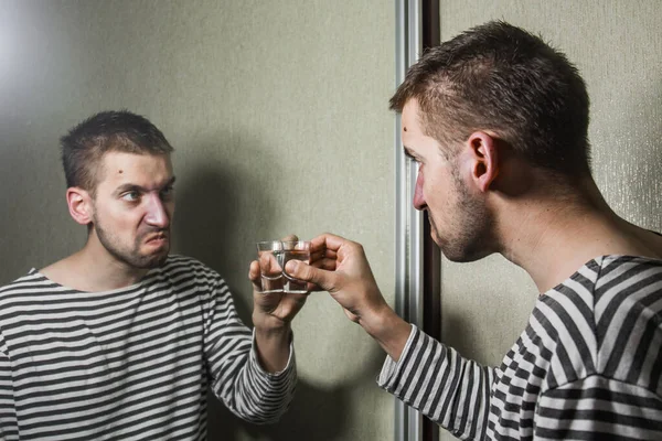 Um homem que sofre de alcoolismo bebe vodka sozinho em casa, ação contra o álcool . — Fotografia de Stock