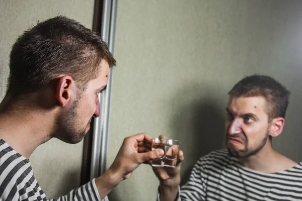 Un hombre que sufre de alcoholismo bebe vodka solo en casa, acción contra el alcohol . — Foto de Stock