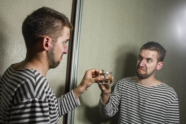 Un hombre que sufre de alcoholismo bebe vodka solo en casa, acción contra el alcohol . — Foto de Stock