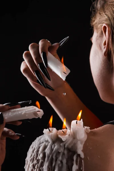 Una chica con el pelo largo en la imagen de una bruja está tratando de prenderse fuego. rituales con velas para hechizo de amor y daño. expulsión de un mal espíritu del cuerpo — Foto de Stock