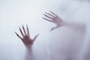 Sisli camların arkasında bir kadının silüeti. Öteki dünyadan gelen kötü ruh konsepti. Kumaştan geçen korkunç ölüm elleri..