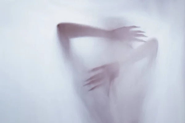 Silhouette di una figura sessuale femminile dietro vetro nebbioso. concetto dello spirito del poltergeist dall'altro mondo. mani spaventose di morte attraverso il tessuto . — Foto Stock