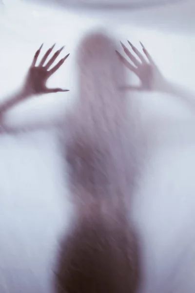 Silhouette einer weiblichen Sexualfigur hinter Nebelglas. Konzept des Poltergeistes von der anderen Welt. Angst einflößende Hände des Todes durch das Gewebe. — Stockfoto