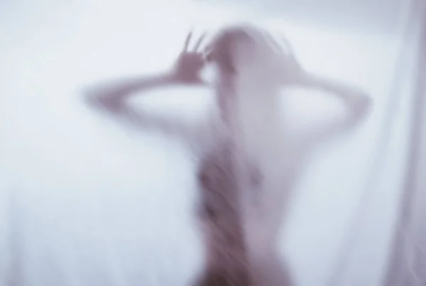 Silueta de una figura sexual femenina detrás de un cristal brumoso. concepto del espíritu de poltergeist del otro mundo. manos aterradoras de la muerte a través de la tela . — Foto de Stock