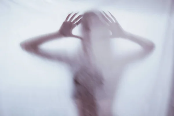 Σιλουέτα μιας γυναικείας σεξουαλικής μορφής πίσω από θολό γυαλί. έννοια του πνεύματος της poltergeist από τον άλλο κόσμο. τρομακτικά χέρια του θανάτου μέσα από το ύφασμα. — Φωτογραφία Αρχείου