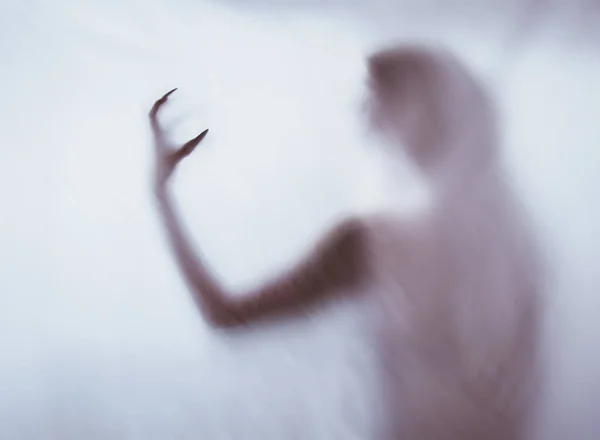 Silhouet van een vrouwelijke seksuele figuur achter mistig glas. begrip van de geest van poltergeist uit de andere wereld. angstaanjagende handen van de dood door het weefsel. — Stockfoto