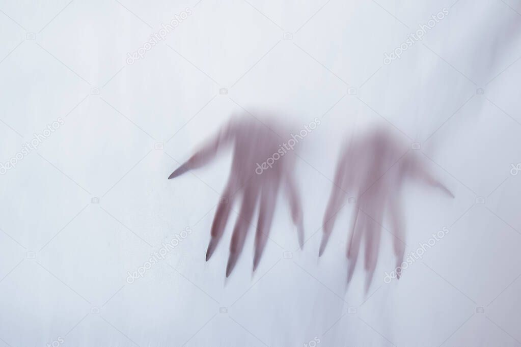 silhouette of a female sexual figure behind foggy glass. concept of the spirit of poltergeist from the other world. frightening hands of death through the fabric.