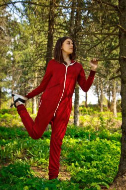 Eşofmanlı güzel, genç bir kız parkta doğayla iç içe spor yapıyor. Sağlıklı yaşam tarzı