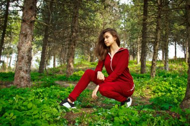 Eşofmanlı güzel, genç bir kız parkta doğayla iç içe spor yapıyor. Sağlıklı yaşam tarzı