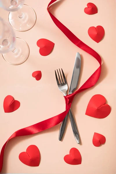 Valentine\'s day romantic date dinner preparation with cutlery, red ribbon and hearts