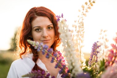 Lupins bir buket arkasında saklanan kırmızı bir kafa kız güzel bir portre