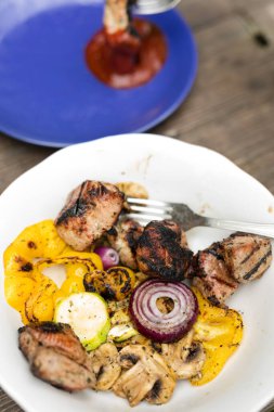 Bir tabak dolusu ızgara sebze ve et İtalyan baharatıyla pişirilmiş, açık havada yenmiş.