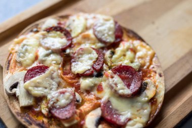 Mozzarella peynirli Pepperoni pizza, beyaz mantar ve sriracha tahta kesme tahtasına konur.