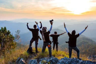 İnsan silueti dağın zirvesinde el ele tutuşur, başarı kavramı.
