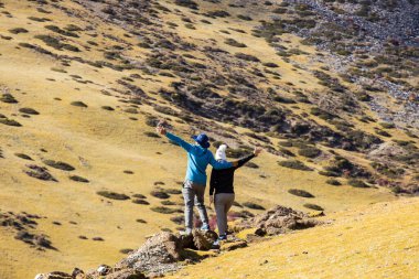 İnsan silueti dağın zirvesinde el ele tutuşur, başarı kavramı.