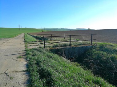 Demir parmaklıklı eski köprü, bir hendek boyunca panel yol ve tarlalar arasında, görüntü