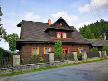 Kır evi tamamen ahşaptan yapılmış, ahşap çitli, asfalt yolun yanında duruyor, görüntü