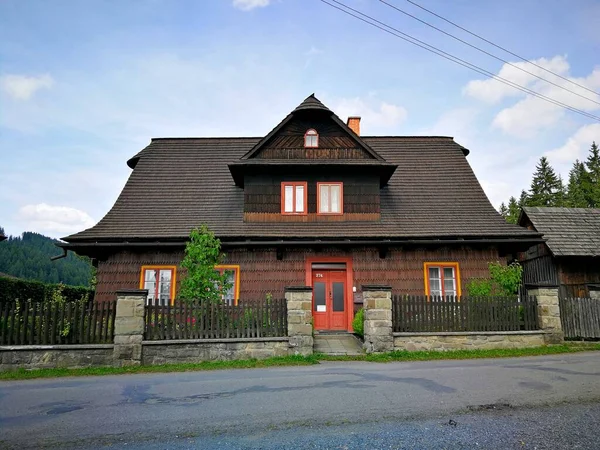 Cottage built of wood, with wooden fence, standing by the asphalt road, image