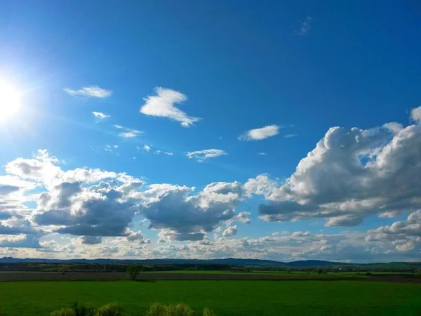 背景には畑や森 山などの田園風景が広がり 青い空が雲や太陽とともに広がっています — ストック写真