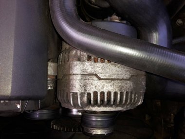 Motor kompartımanında motor alternatörü, plastik örtü ve hortumla birlikte, görüntü