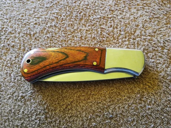 Pocket knife with wooden handle, closed, placed on brown terry cloth, image